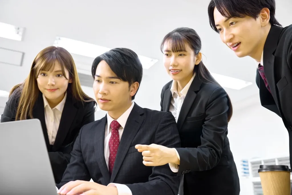 パソコンを見ながら採用状況を確認している4人のビジネスパーソン