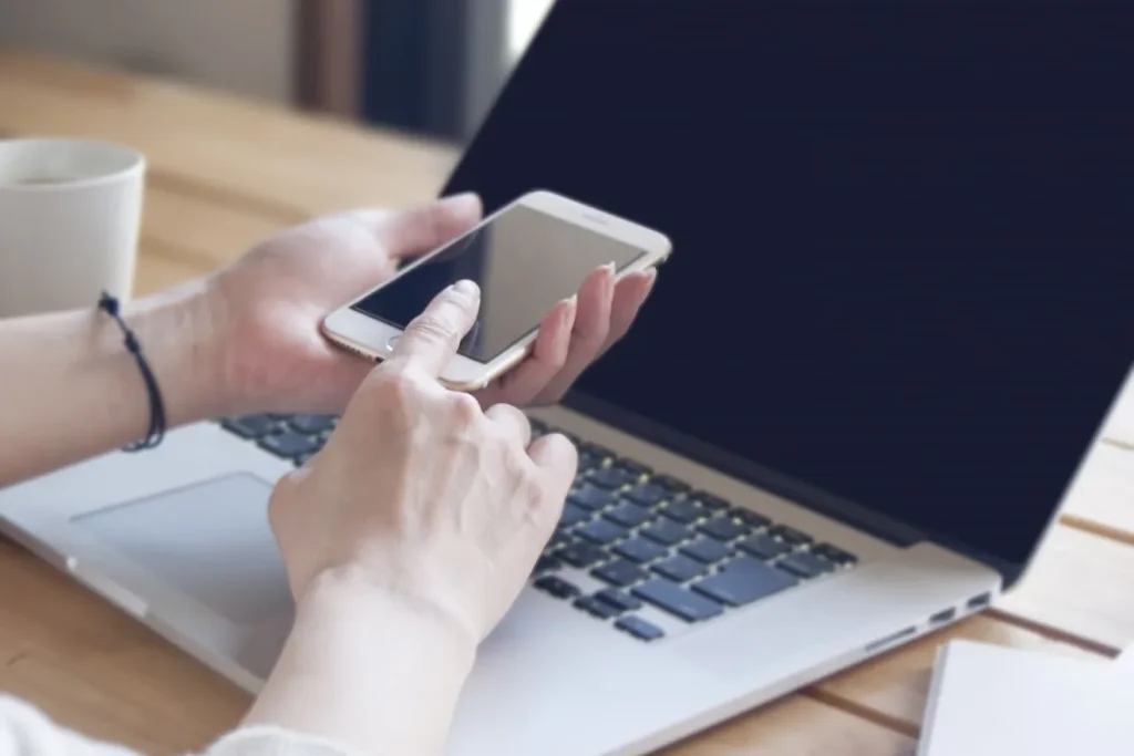 毎朝スマートフォンとパソコンを確認する女性