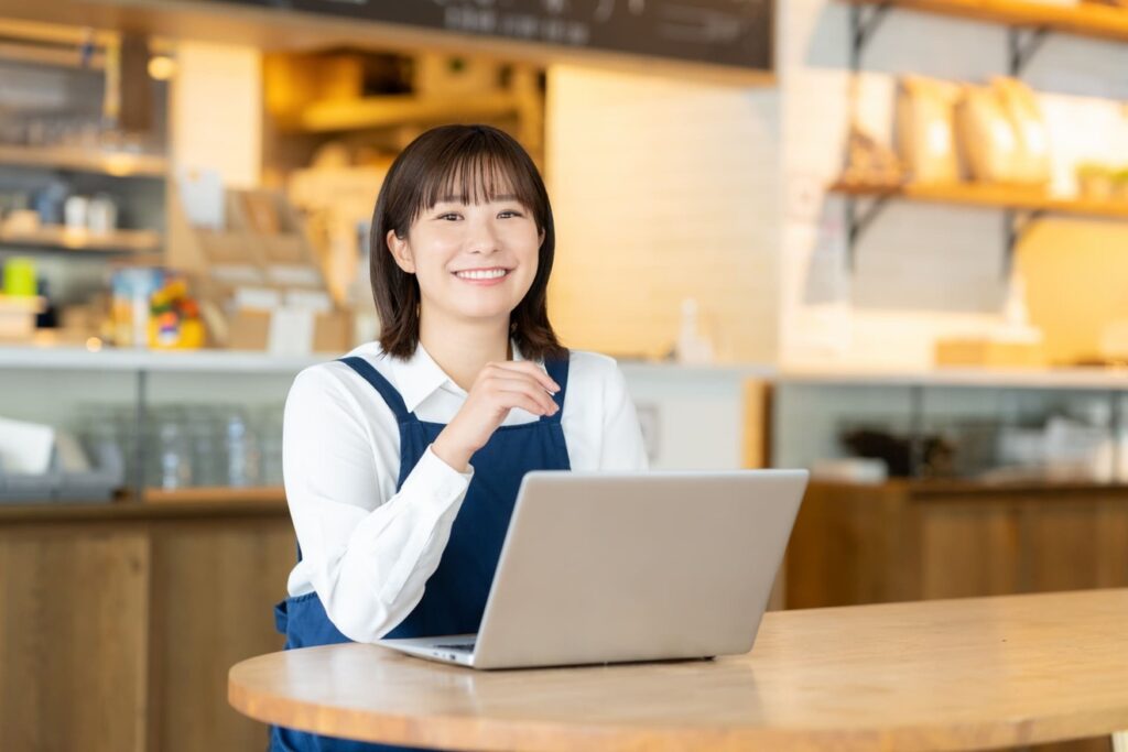パソコンで仕事をしている笑顔のカフェ店員