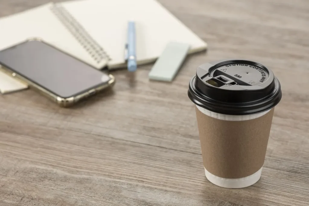 テイクアウトで注文したコーヒーとスマートフォン