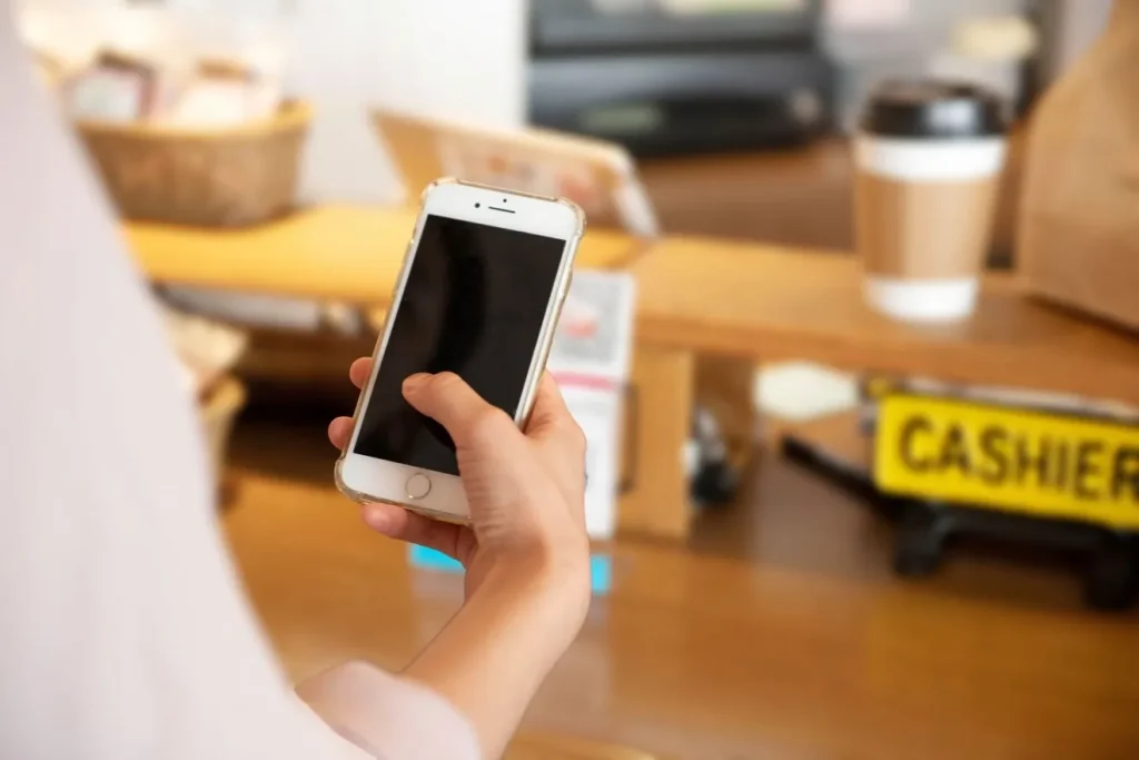 スマートフォンを持って店に入る女性