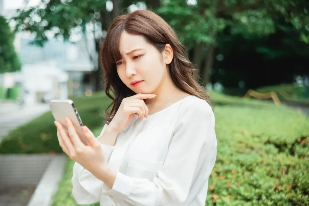 不快な顔をしながらスマートフォンを見る女性