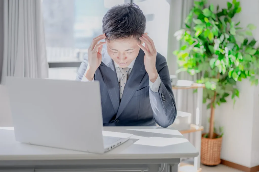顧客から返事が来なくて頭を抱える男性